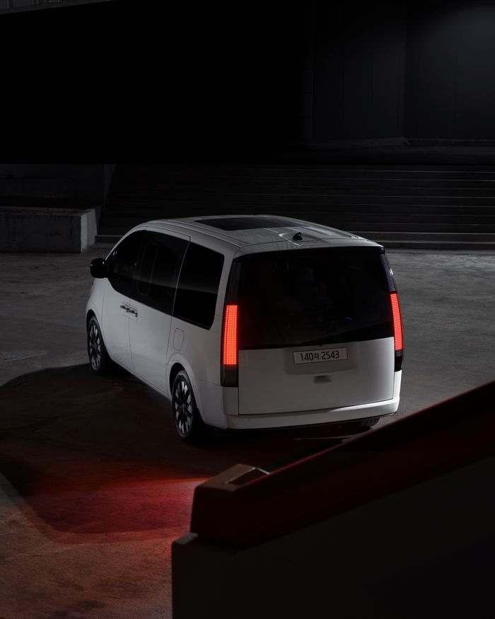 A sleek white Hyundai Staria captured in a dimly lit urban environment at night, highlighting its modern design.